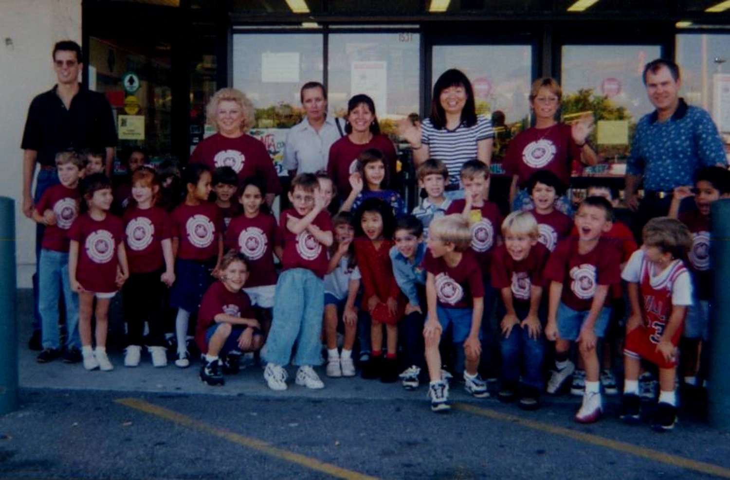 Students and staff in matching red shirts in front of the school in the 1990s