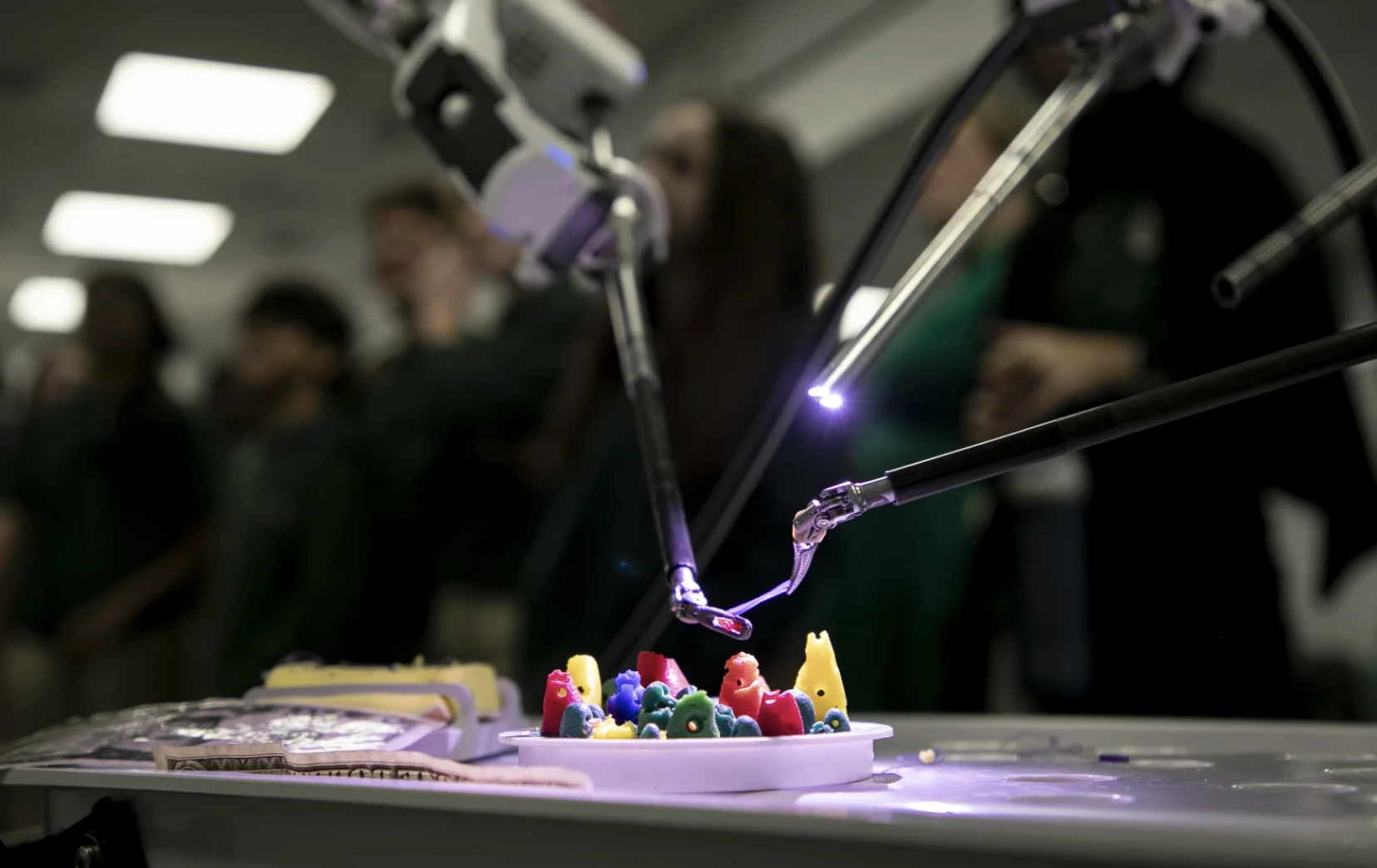 Surgical robot arms working with small colored pieces during a demonstration
