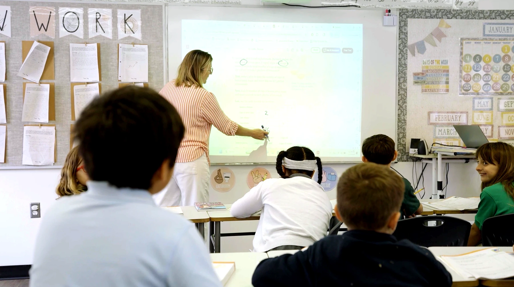 A teacher at the board working through a problem with her class